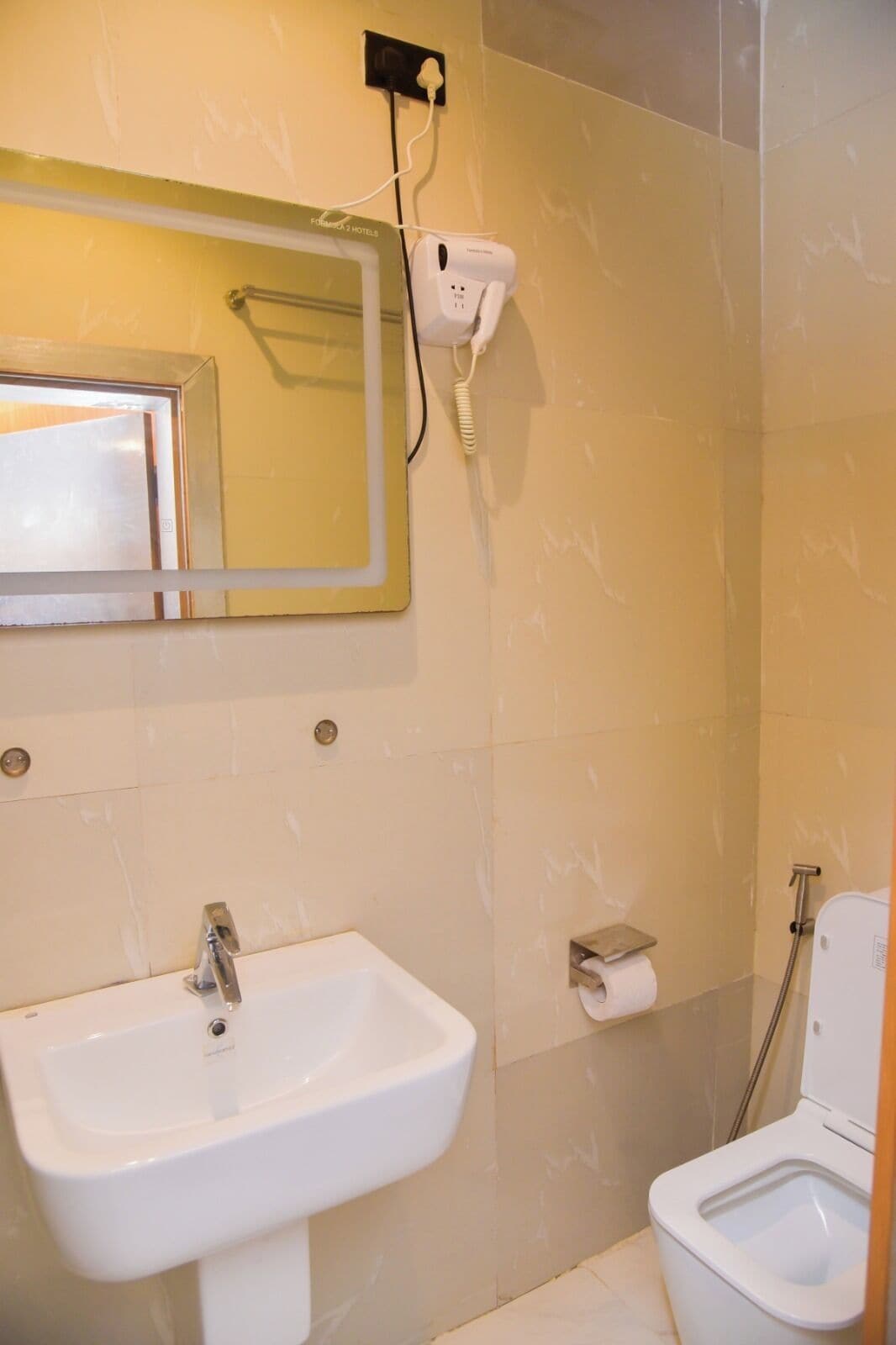 A bathroom with a sink, toilet, and a hairdryer mounted on the wall.