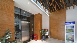 Un espace d’accueil moderne, doté d’un distributeur automatique, d’une plante en pot et d’un ascenseur à cabine en verre.