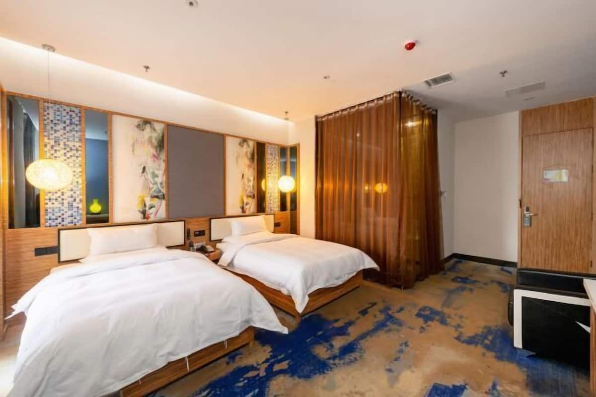 Habitación de hotel con dos camas, un espejo grande, un armario de madera y un televisor.