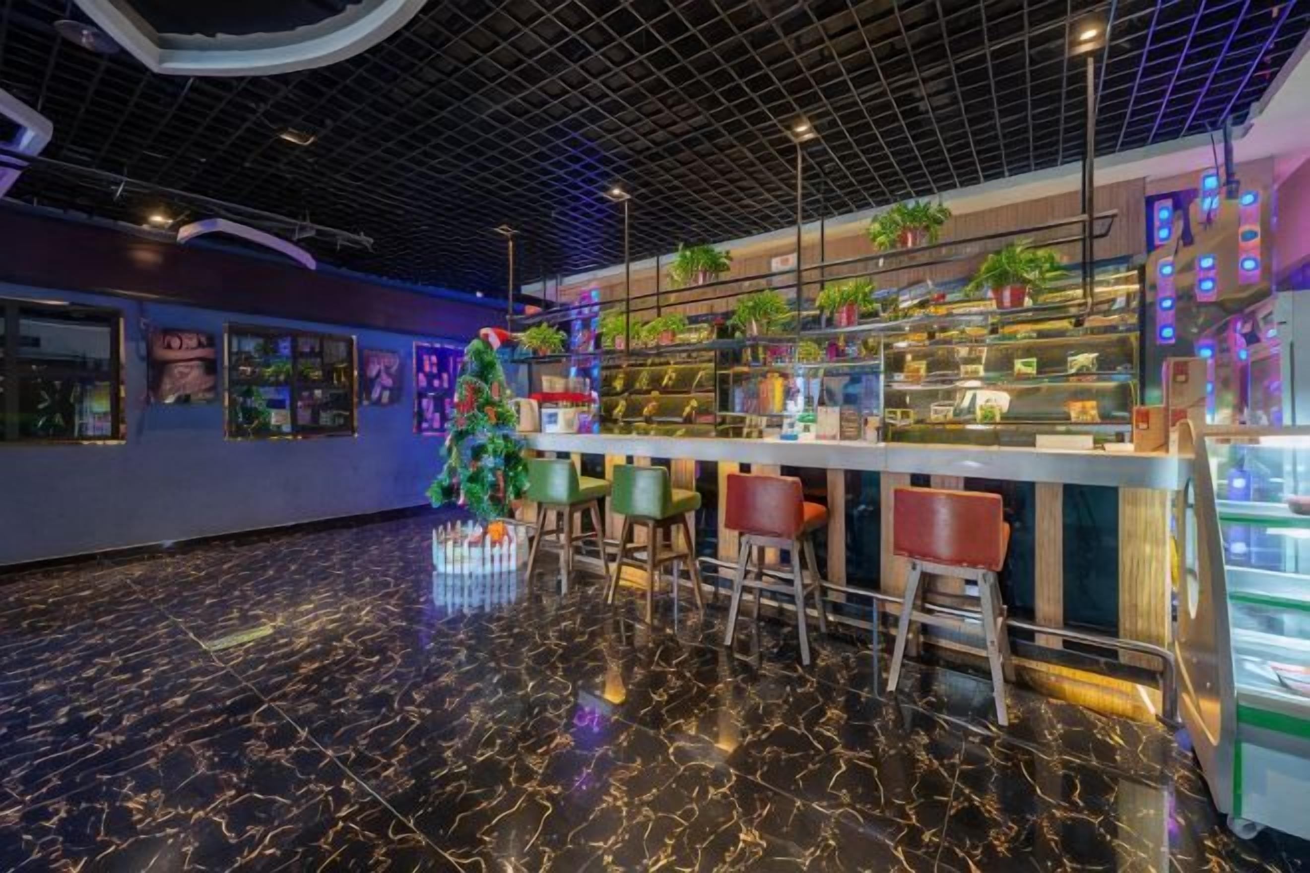 Uma área de bar com piso de mármore, banquetas e um pinheiro de Natal.