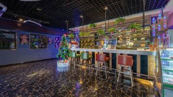 Uma área de bar com piso de mármore, banquetas e um pinheiro de Natal.