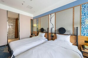 Habitación de hotel con dos camas, cabecera de madera, mesita de noche con teléfono y vista al baño.