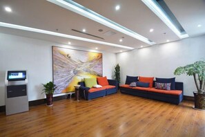 A reception area with a reception desk, a large abstract painting, a sofa with cushions, and a potted plant.