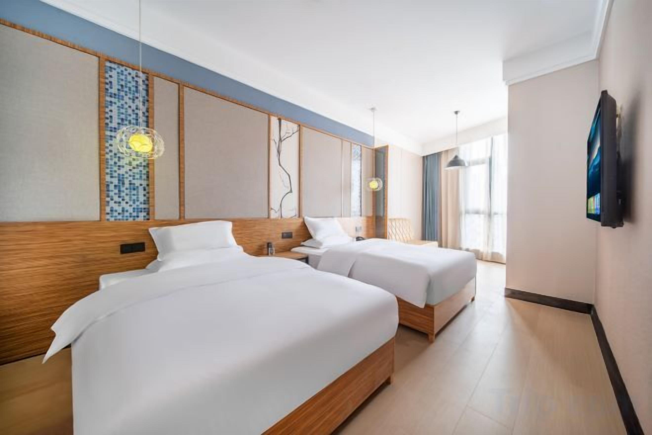 Habitación de hotel con dos camas, un ventanal grande y un diseño moderno.