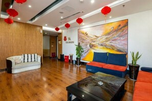 Un vestíbulo con piso de madera, un sofá, una mesa de centro y un cuadro abstracto grande.