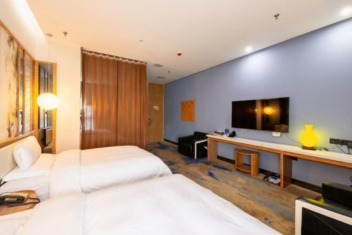 Una habitación de hotel con dos camas, un escritorio, una silla, un televisor y una lámpara.
