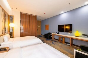 Una habitación de hotel con dos camas, un escritorio, una silla, un televisor y una lámpara.