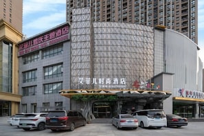 A hotel with a curved facade, multiple parking spaces, and a prominent entrance.