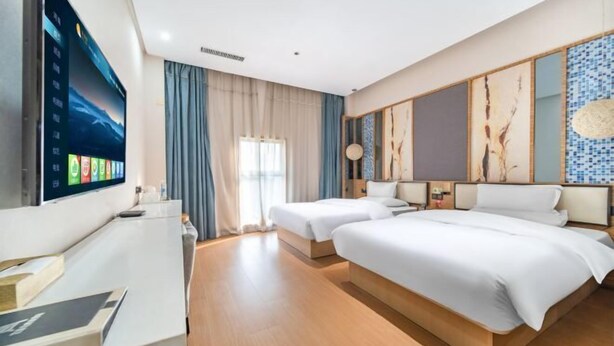 Une chambre d’hôtel avec un grand lit, un bureau avec un ordinateur et un téléviseur fixé au mur.