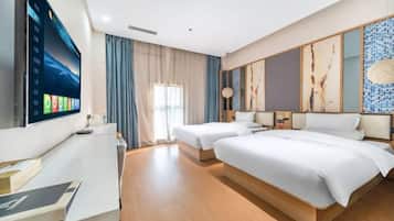 Una habitación de hotel con cama, escritorio, televisor y ventana con cortinas.