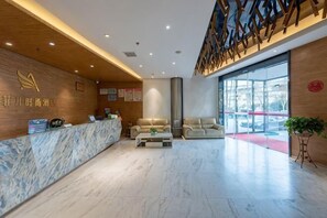 A modern hotel lobby with a reception desk, seating area, and large windows. - Aifeier Shishang Hotel (Zhengzhou)