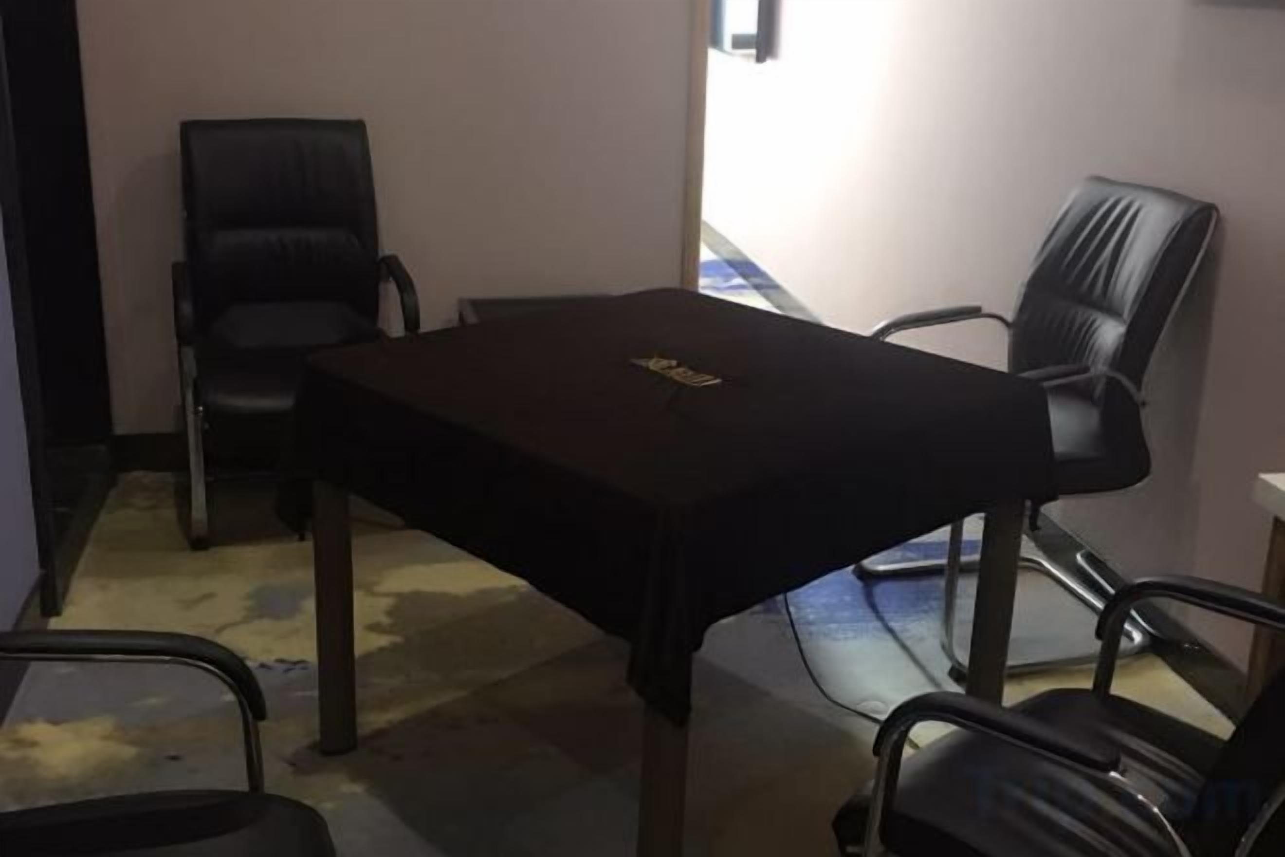 Un salón de conferencias con una mesa y cuatro sillas.