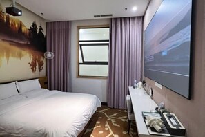 Habitación de hotel con cama, escritorio, ventana grande y televisor de pared.