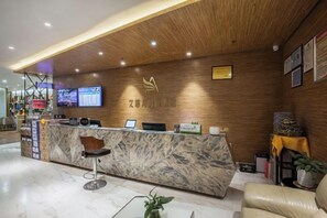 Una recepción con mostrador de mármol, techo de madera y una pantalla digital encima.