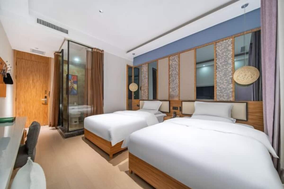 Habitación de hotel con dos camas, un escritorio y un ventanal corredero que da a un balcón.