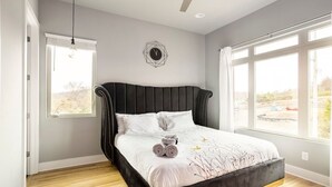A bedroom with a large bed, a window with a view, a wall clock, and a ceiling fan. - Tailgater's Dream! Rooftop w/ TV + Fire + Lights (Nashville)
