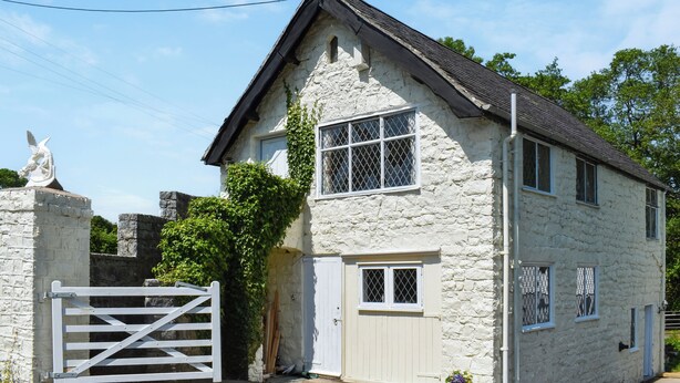 A stone house with a white door, a small window with a lattice, and a statue of an angel. - 2 bedroom accommodation in Llanarmon-Yn-Ial (Llanarmon-Yn-Ial)