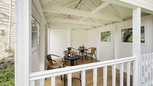 A covered outdoor seating area with a white railing, a table with chairs, and a view of the surrounding landscape. - 2 bedroom accommodation in Llanarmon-Yn-Ial (Llanarmon-Yn-Ial)