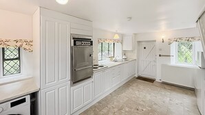 A modern kitchen with white cabinetry, a stainless steel refrigerator, and a tiled floor. - 2 bedroom accommodation in Llanarmon-Yn-Ial (Llanarmon-Yn-Ial)