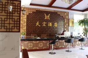 Un área de recepción con un panel de pared de madera, un mostrador de recepción y tres taburetes de bar.