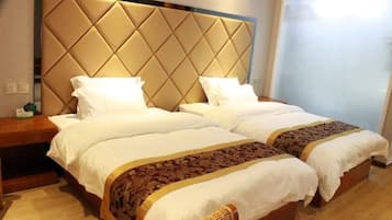 Uma cama de casal com cabeceira acolchoada, duas mesas de cabeceira e um cobreleito estampado.