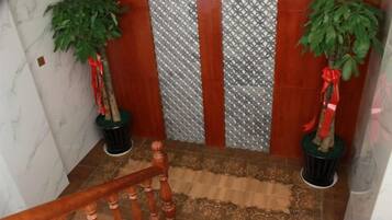 Una escalera con barandilla de madera, dos macetas y paneles decorativos en la pared.