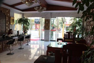 Un vestíbulo de hotel con mostrador de recepción, zona de estar y amplios ventanales que dejan entrar luz natural.