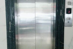 An elevator with a metallic interior and a control panel with a red indicator light. - Ruili Tianhong Hotel (Ruili)