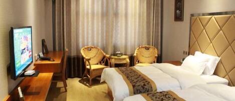 A hotel room with two beds, a desk with a television, and two wicker chairs.