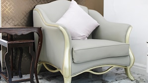 Un fauteuil gris clair avec un coussin blanc, placé à côté d’une petite table en bois.