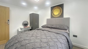 Une chambre à coucher comprenant un lit, une coiffeuse avec un miroir, une armoire et un élément décoratif mural.