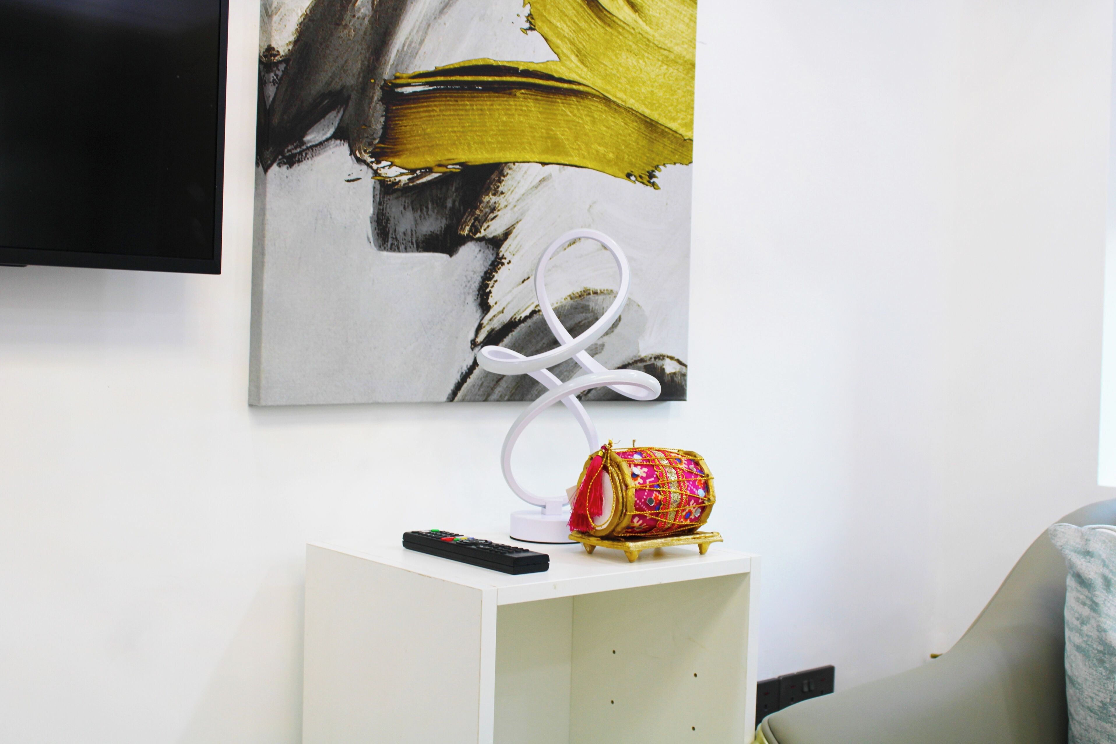 Une pièce moderne avec une console blanche, une table basse aux couleurs vives et un tableau accroché au mur.
