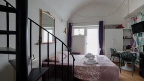 A bedroom with a bed, a desk, a chair, a TV, and a wardrobe.