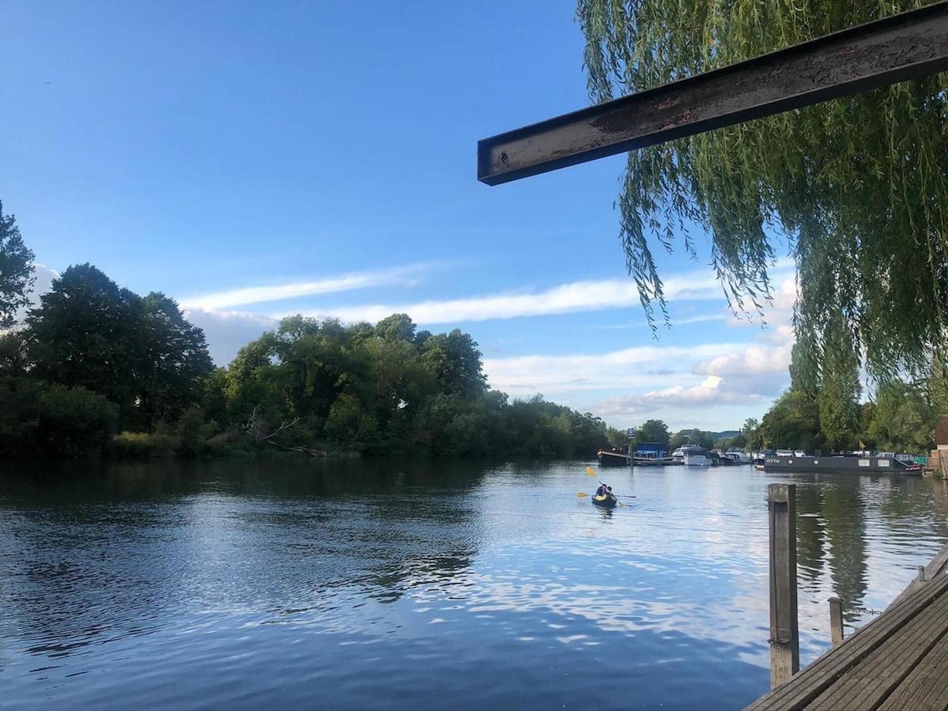 Un río tranquilo con un muelle y un kayak en el agua.