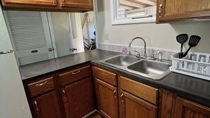 Una cocina con armarios de madera, un lavamanos de acero inoxidable y una ventana sobre el lavamanos.