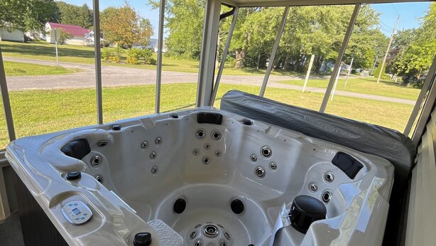 Un jacuzzi con múltiples chorros, un panel de control y vistas a una zona residencial a través de amplios ventanales.