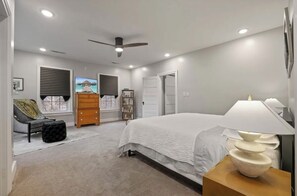 Relax in this serene bedroom with a large bed, ceiling fan, and comfortable seating area.