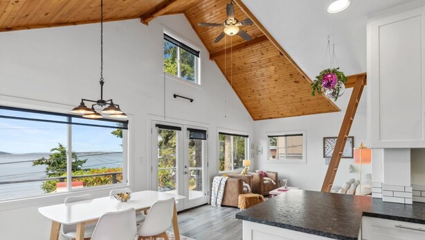 Una cocina amplia con una isla grande, techo de madera y ventanas amplias que dan a un paisaje exterior.