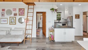 Un loft espacioso con techo alto, cama de altillo, zona de cocina y comedor.