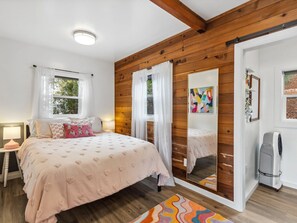 Cozy retreat with a large bed, wooden paneling, and a large mirror.