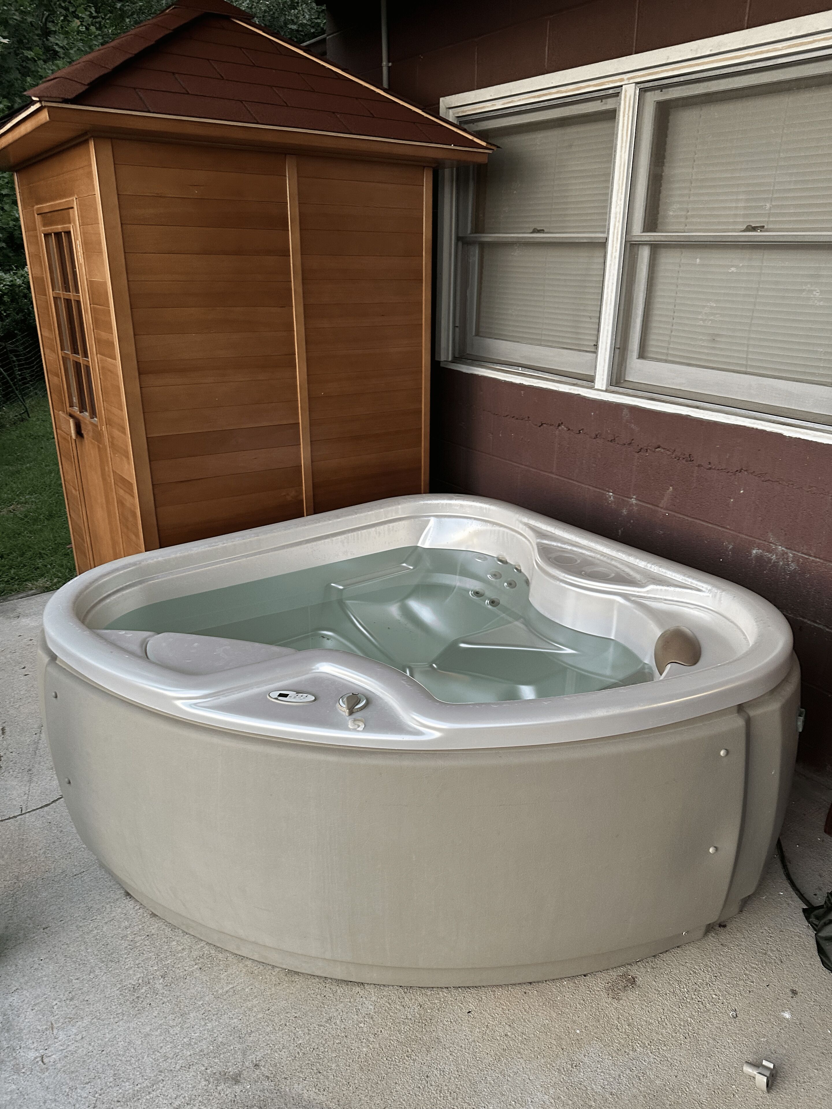 A hot tub outdoors next to a wooden shed and a garage door.
