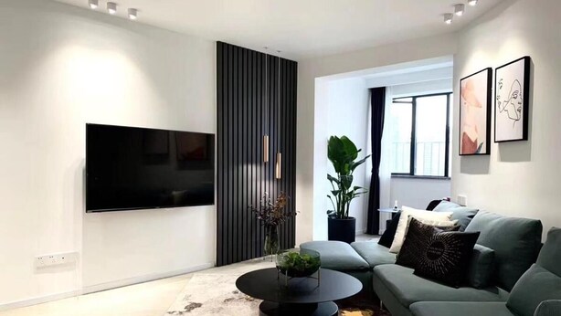 Una sala moderna con televisor de pantalla plana, un sofá gris, una mesa de centro y una planta grande en maceta.