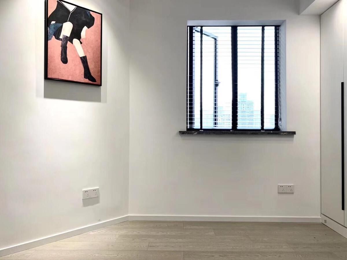 Ein Zimmer mit großem Fenster, weißen Wänden und Holzboden.