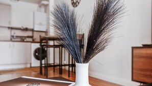 A white vase with a textured, feather-like decoration on a glass table in a modern kitchen setting. - Modern 2-bed Apartment in Stratford (London)