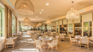 A spacious restaurant with high ceilings, large windows, and wicker furniture. - GR Solaris Lighthouse Los Cabos (San José del Cabo)
