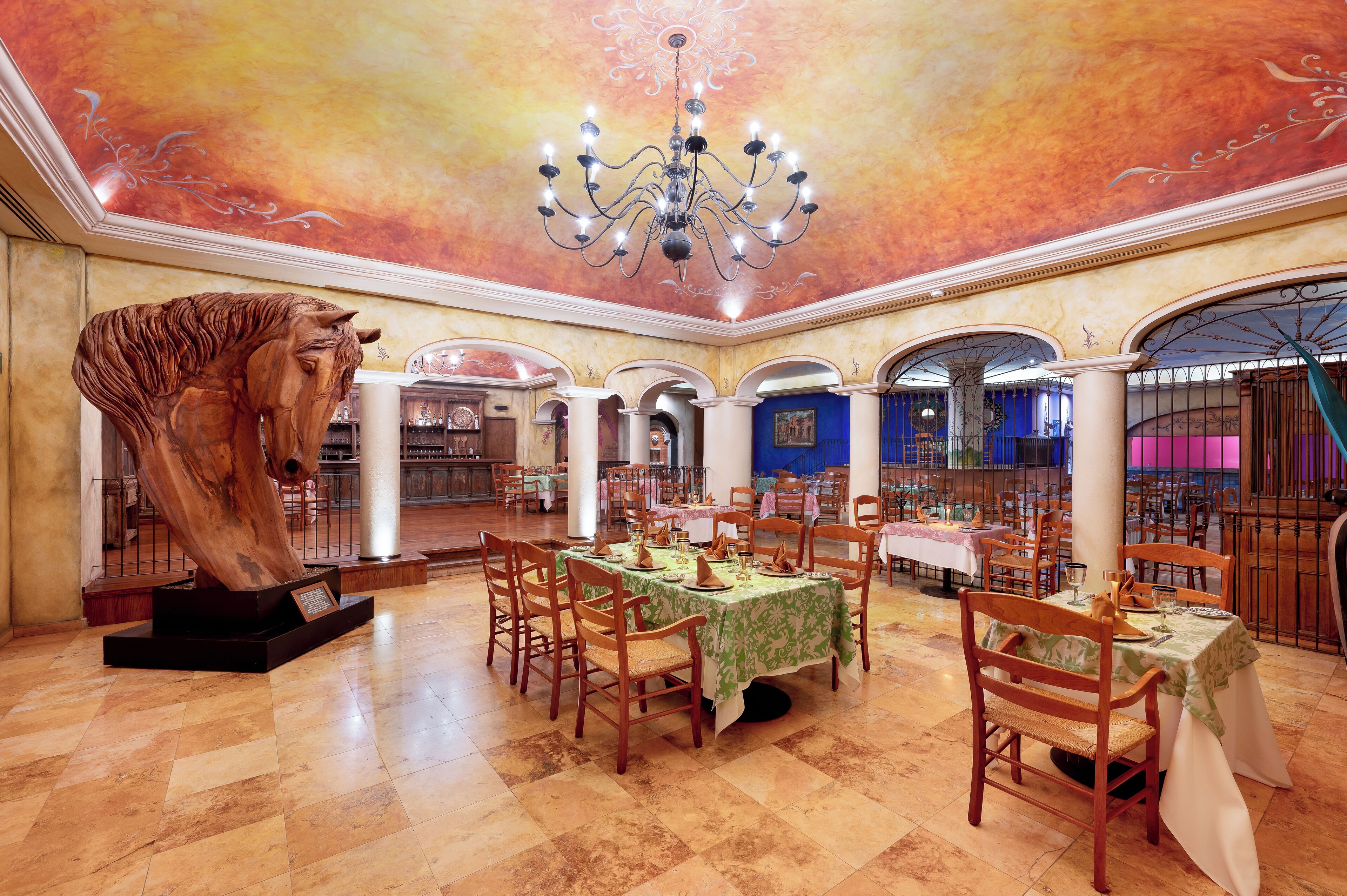 A spacious dining area with multiple tables, chairs, and a chandelier.
