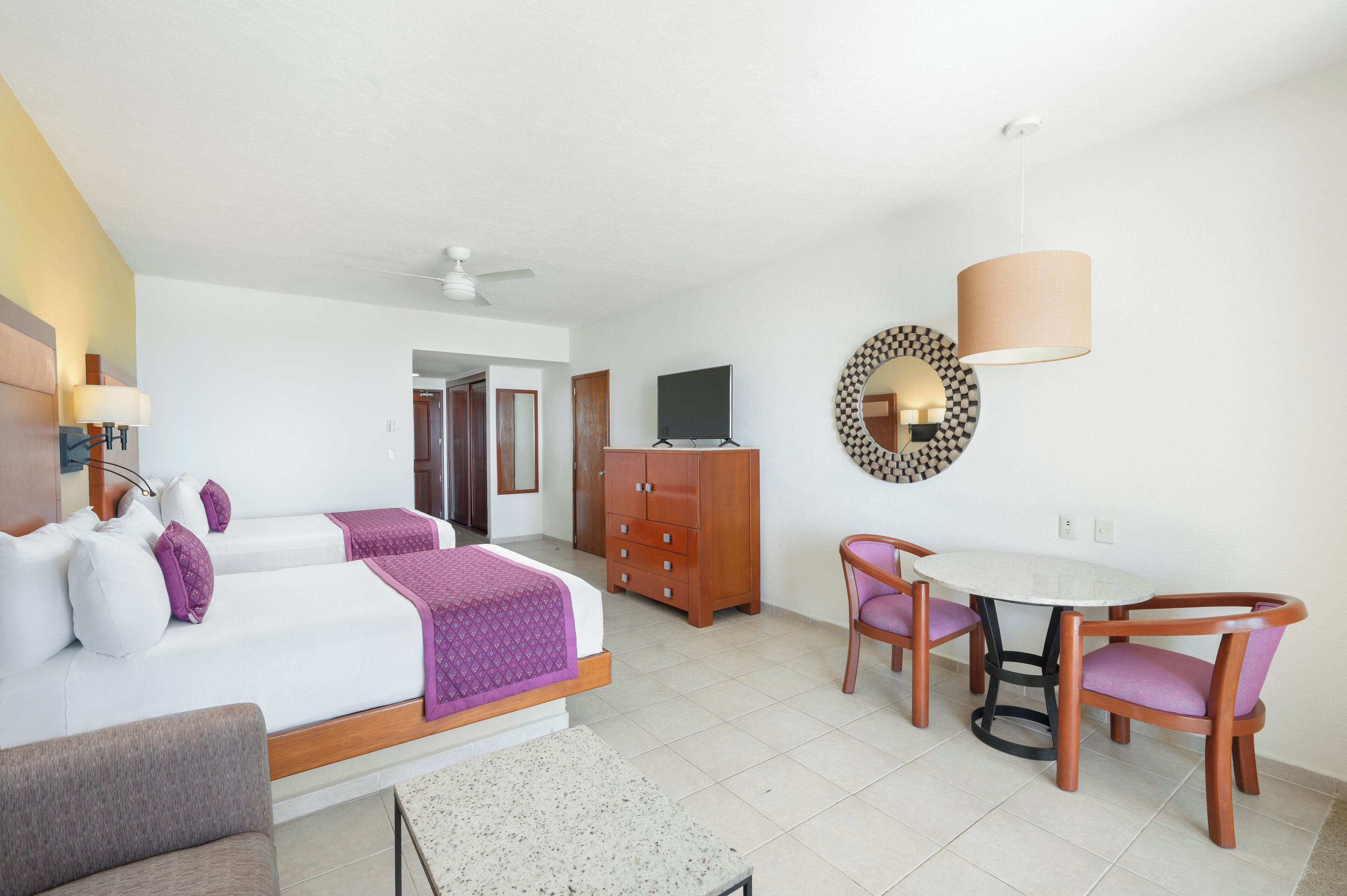 A hotel room with a bed, a desk, a chair, a TV, and a wardrobe.