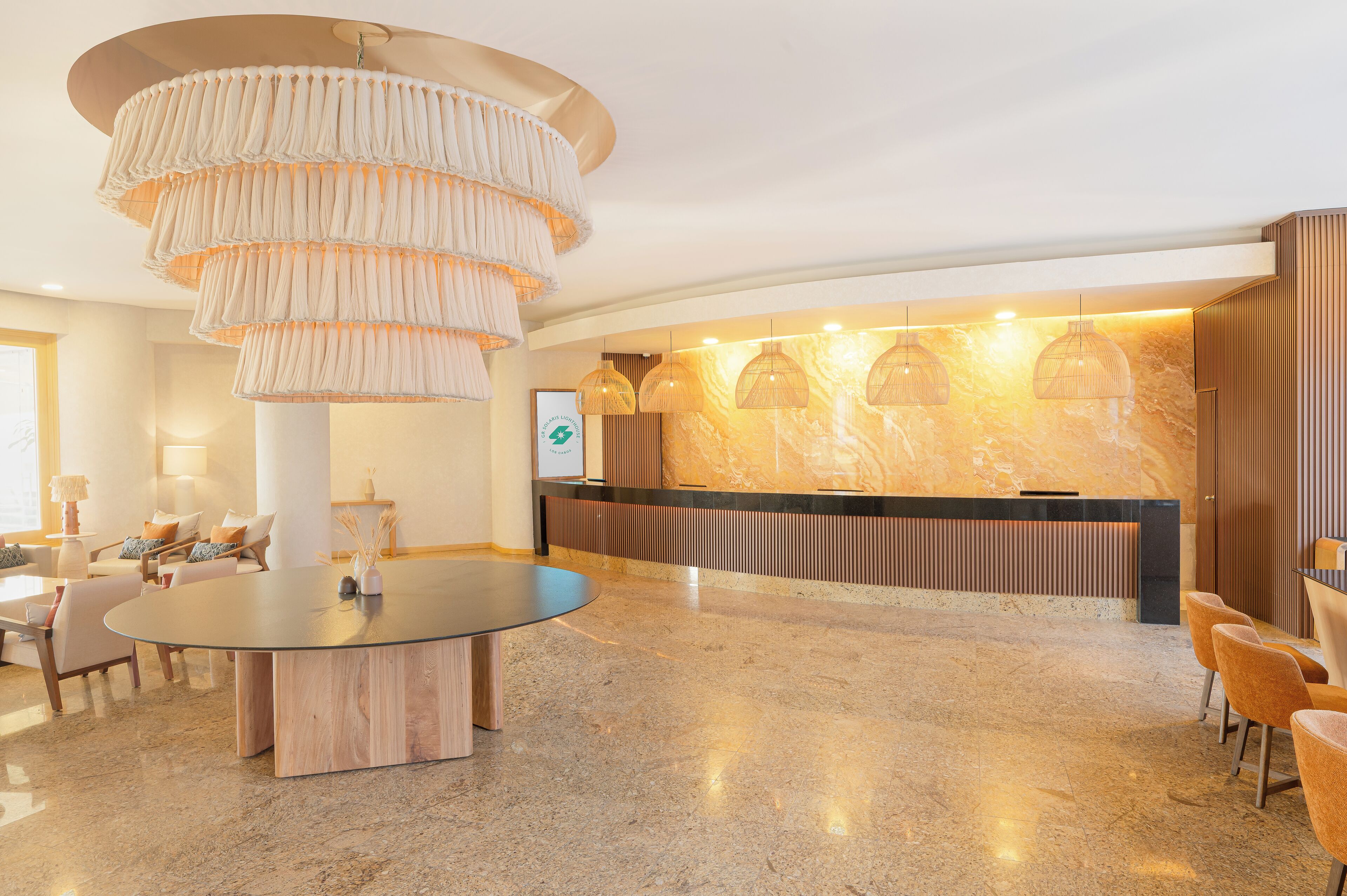 Una hall moderna con una scrivania della reception, un tavolo rotondo con sedie e un grande lampadario.