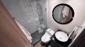 A modern bathroom with a glass shower enclosure, a toilet, and a sink with a mirror above it. - Amplio apt en poblado by Hoost APT 701 (Medellín)