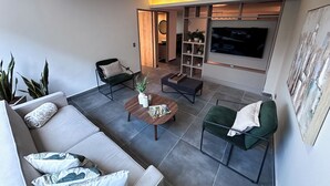 A modern living room with a sofa, a coffee table, a TV, and a bookshelf. - Amplio apt en poblado by Hoost APT 701 (Medellín)
